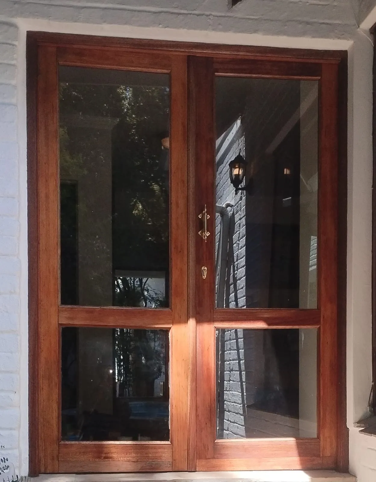 The same french doors finished, the hardwood a deep even red-brown with the brass handle and escutcheon cleaned up