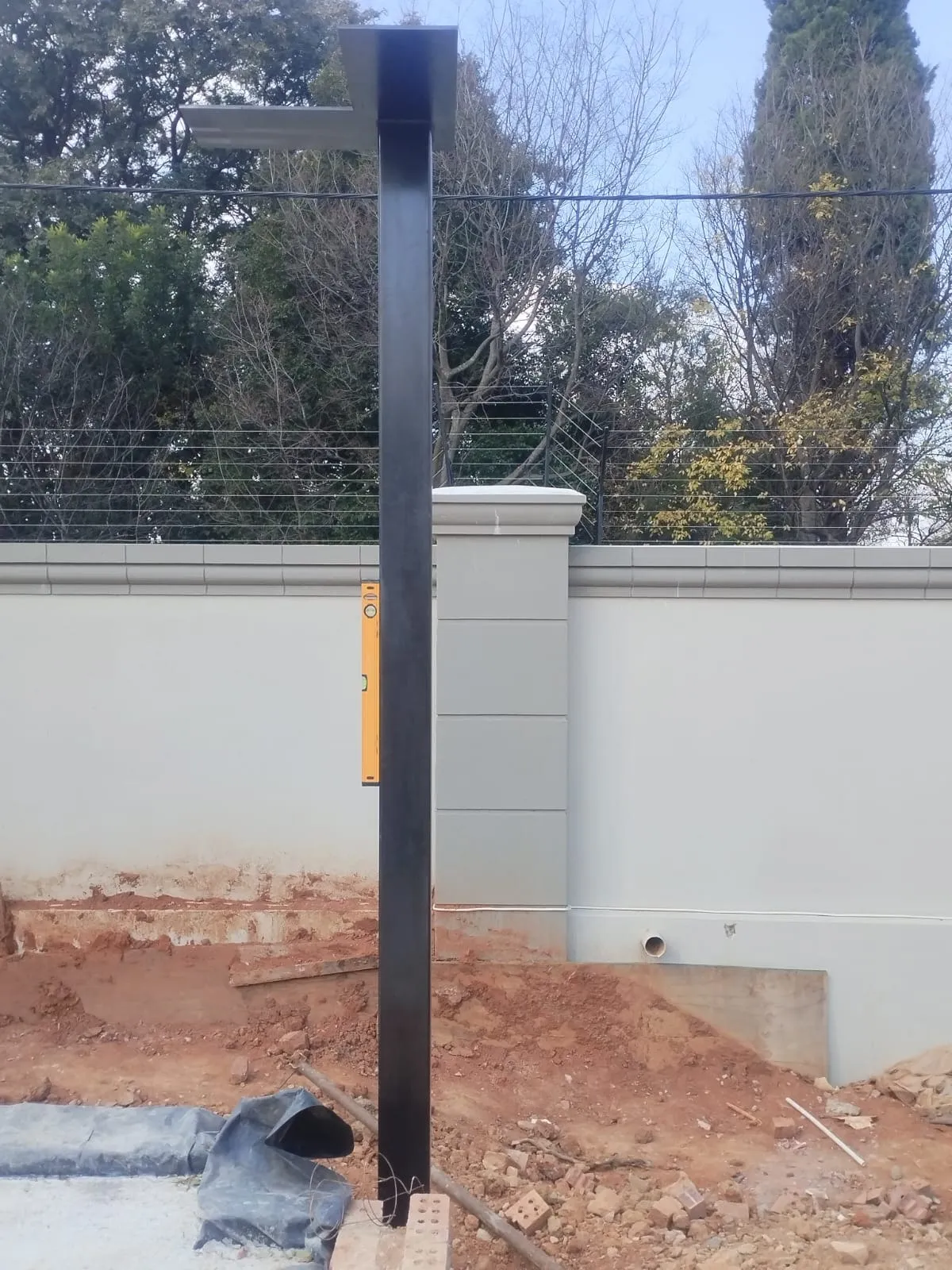 A structural column being checked for plumb with a spirit level held against the web